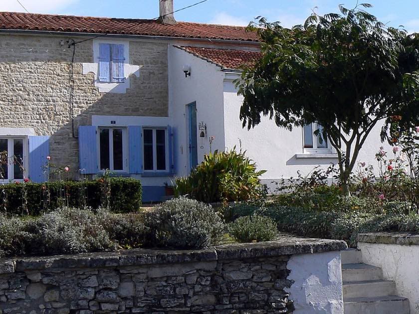 Maison de village en pierre avec volets bleus et jardin